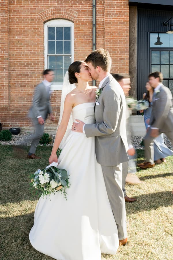A bride and groom share a kiss during their outdoor wedding ceremony.